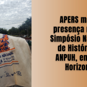 Imagem dividida em duas partes. À esquerda, uma fotografia mostra uma mão segurando uma ecobag bege com a arte do 33º Simpósio Nacional de História da ANPUH, realizado entre os dias 13 e 18 de julho de 2025, em Belo Horizonte, Minas Gerais. A arte impressa na sacola apresenta uma ilustração estilizada de uma figura feminina formada por linhas coloridas em laranja e azul, transmitindo movimento. Abaixo da ilustração, estão os logotipos da ANPUH, UFMG, FAFICH e CAPES.

Ao fundo, vê-se um céu nublado, árvores e parte de edifícios em uma área externa, possivelmente no campus universitário onde ocorreu o evento.

À direita da imagem, sobre um fundo em tom bege degradê, está escrito em letras grandes e pretas:
"APERS marca presença no 33º Simpósio Nacional de História da ANPUH, em Belo Horizonte".