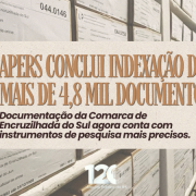 Imagem de divulga&ccedil;&atilde;o do APERS. Ao fundo, aparecem estantes de arquivo deslizantes preenchidas com caixas de documentos identificadas por etiquetas. Sobre a fotografia, h&aacute; um quadro retangular de cor clara com o texto: &ldquo;APERS conclui indexa&ccedil;&atilde;o de mais de 4,8 mil documentos&rdquo;. Abaixo, em destaque menor, l&ecirc;-se: &ldquo;Documenta&ccedil;&atilde;o da Comarca de Encruzilhada do Sul agora conta com instrumentos de pesquisa mais precisos&rdquo;. Na parte inferior da imagem, est&aacute; a marca dos 120 anos do Arquivo P&uacute;blico do Estado do Rio Grande do Sul. A composi&ccedil;&atilde;o utiliza tons bege e marrons, remetendo &agrave; preserva&ccedil;&atilde;o documental e &agrave; pesquisa hist&oacute;rica.